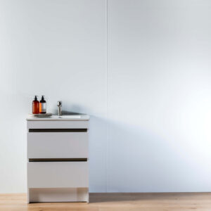 A white panel wall joined with a white joiner. A white vanity in front with soap and a wooden floor in the forefront.